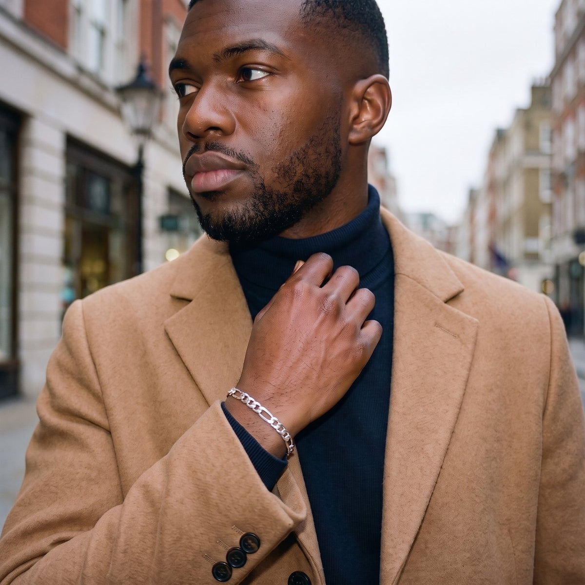 Man in a camel coat in Marylebone at dusk wearing a silver Figaro bracelet