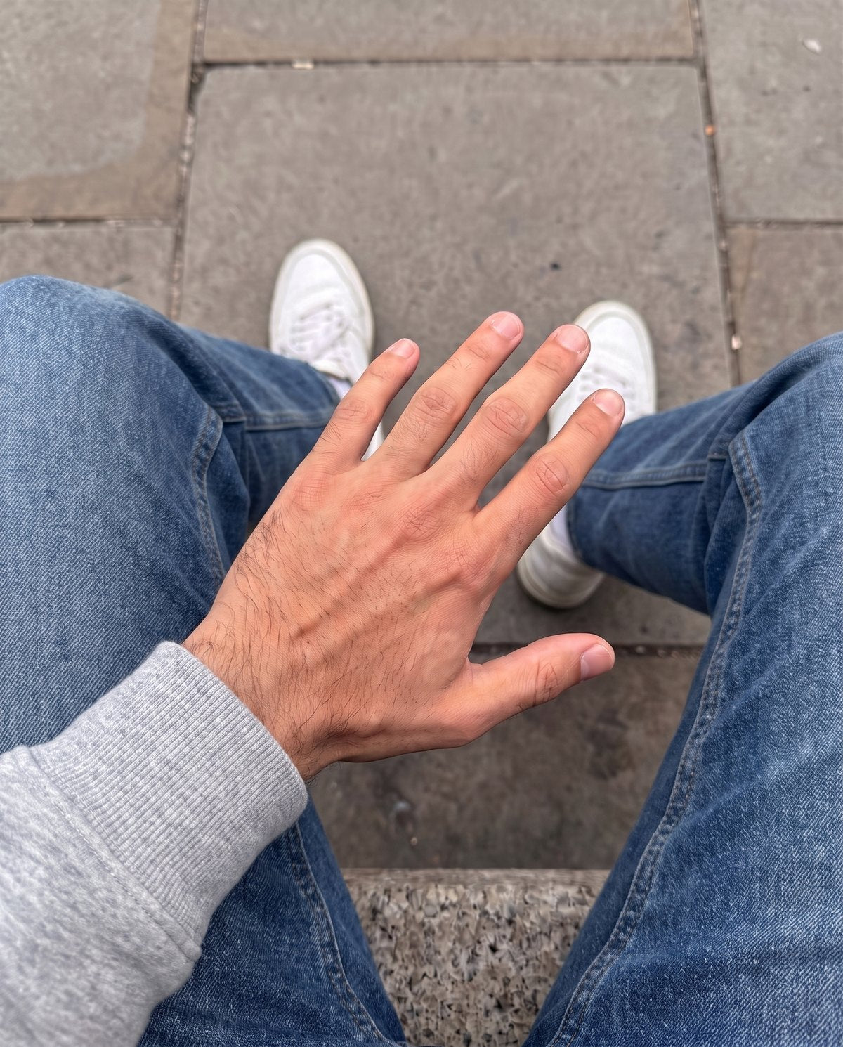 The same hand in a grey hoodie and jeans with no jewellery